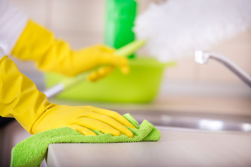 Close up of female hands with protective gloves wiping kitchen countertop