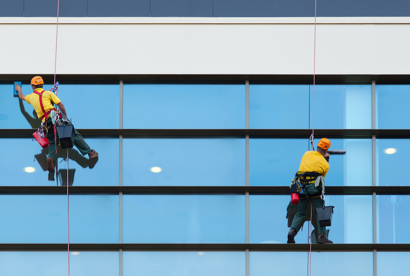 Two workers washing windows of the modern building.